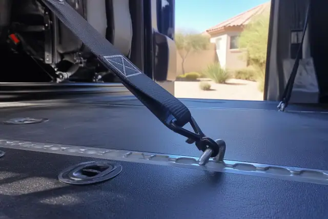 Heavy-duty four-point tie-down strap attached to a vehicle floor track in Phoenix, AZ.