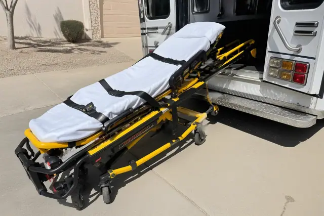 Medical transport stretcher being loaded into a vehicle on a driveway in Peoria, AZ.
