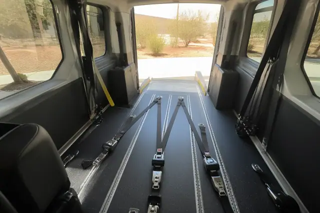 Interior of a medical transport van with wheelchair tie-down straps and desert views in Phoenix, AZ.
