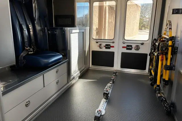 Interior of an ambulance patient compartment with medical equipment and safety restraints in Phoenix, AZ.