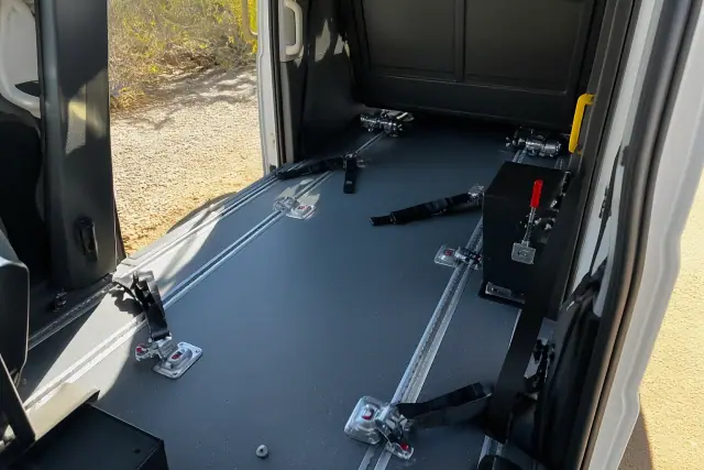 Wheelchair tie-down station inside a medical transport vehicle in Phoenix, AZ, with desert scenery visible outside.
