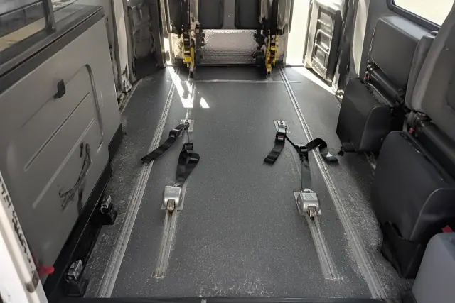 Wheelchair securement station with four-point tie-down straps inside a medical transport vehicle in Phoenix, AZ.