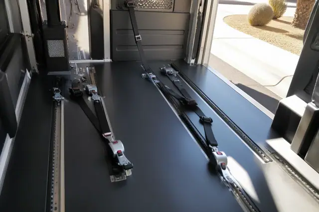 Wheelchair securement station with four-point tie-down straps inside a medical transport vehicle in Surprise, AZ.
