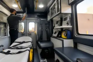 Technician cleaning a handrail inside a medical transport van cabin in Phoenix, AZ.