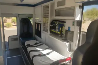Rear patient cabin with storage cabinets and safety restraints in a transport van in Phoenix, AZ.