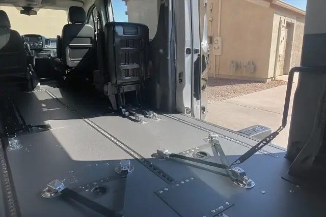 Wheelchair securement station with tie-down straps inside a medical transport van in Phoenix, AZ.