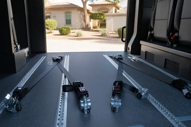 Wheelchair securement station with four-point tie-down straps in a medical transport vehicle in Sun City, AZ.