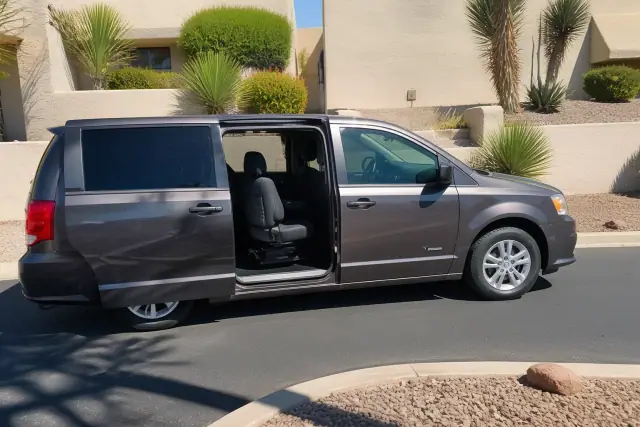 Medical transport van with side doors open for curbside passenger boarding at a house in Mesa, AZ.