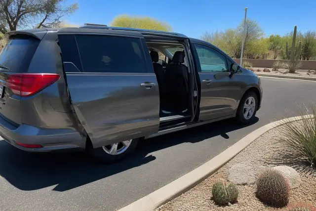 Medical transportation vehicle with open side doors for curbside pickup in Phoenix, AZ, near desert landscaping.