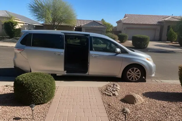 Medical transport vehicle with sliding doors open for boarding on a street in Peoria, AZ with desert landscaping.