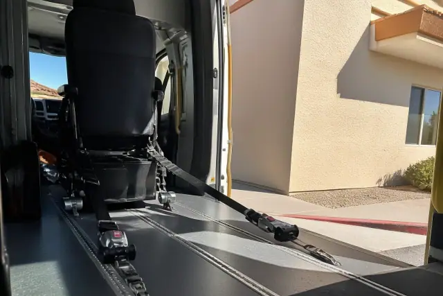 Heavy-duty tie-down straps secured to a medical transport vehicle floor in Glendale, AZ.