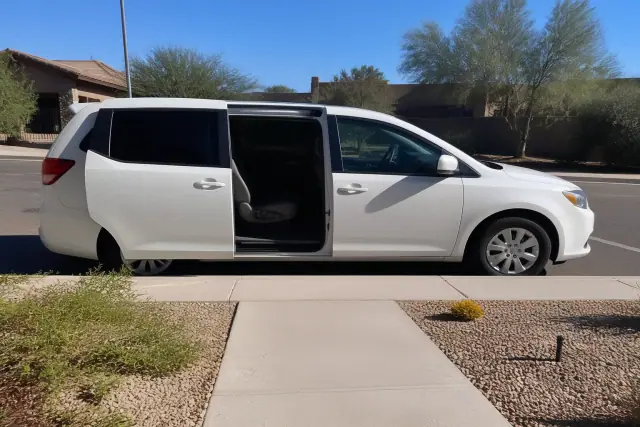 Medical transport vehicle with open side doors for curbside pickup in Surprise, AZ, against a desert landscape.