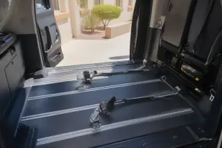 Interior floor tracks with four-point tie-down straps in a medical transport van parked in Phoenix, AZ.