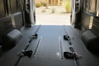 Interior floor tracking and four-point tie-down straps inside a transport van in Phoenix, AZ.