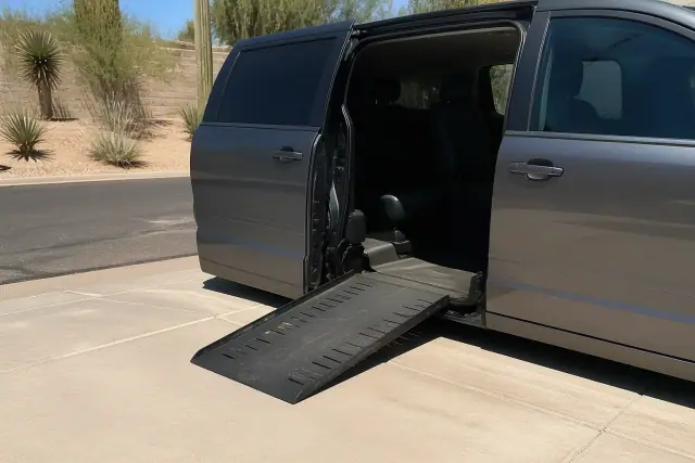 A vehicle parked with its sliding doors open and ramp deployed for boarding in Phoenix, AZ, set against desert landscaping.