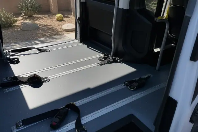 Interior of a medical transport van showing wheelchair tracks and tie-down straps in Phoenix, AZ.