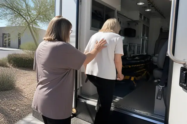 An escort assists a passenger through a vehicle doorway for medical transport in Phoenix, AZ.