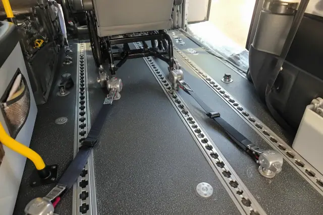 Four-point tie-down strap locking mechanism inside a medical transport vehicle in Phoenix, AZ.