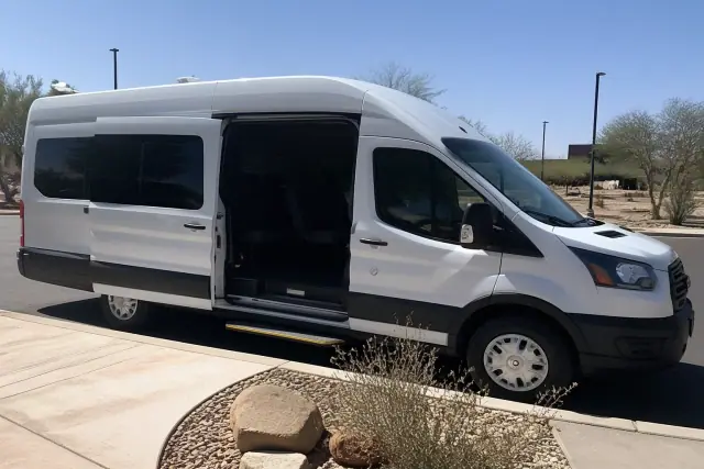 Medical transport vehicle parked at a curb in Phoenix, AZ, with side doors open for boarding.