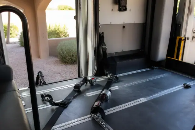 Wheelchair securement station with floor tracking and tie-down straps in a medical transport van in Mesa, AZ.