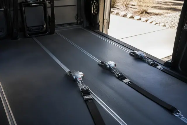 Wheelchair securement station with four-point tie-down straps inside a medical transport van in Tempe, AZ.