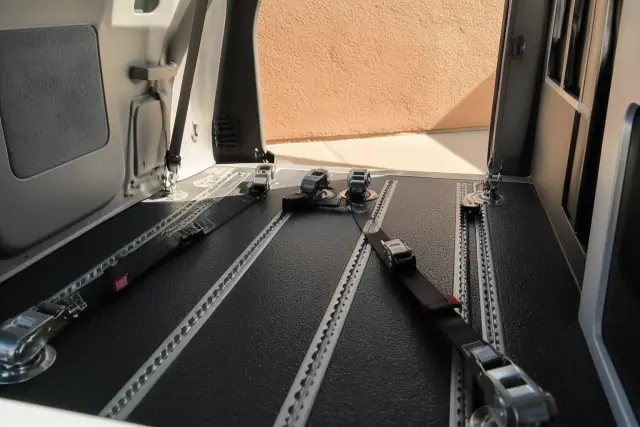 Four-point wheelchair tie-down straps anchored to a vehicle floor in Glendale, AZ.