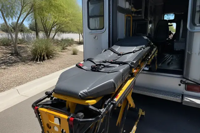 Medical transport stretcher with safety belts and locking mechanism secured at a vehicle in Tempe, AZ.