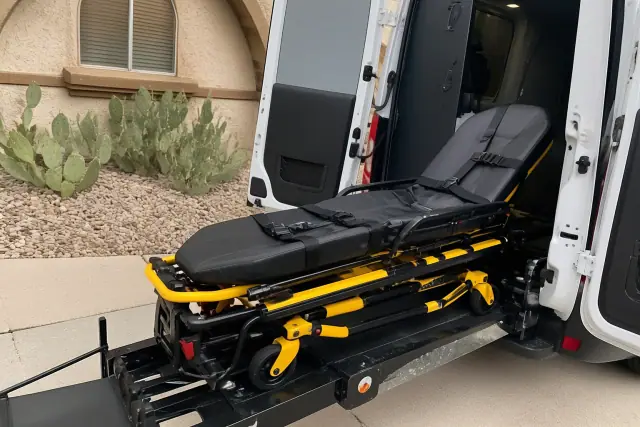 A medical transport stretcher with safety belts and locking mechanisms at a residential building in Phoenix, AZ.