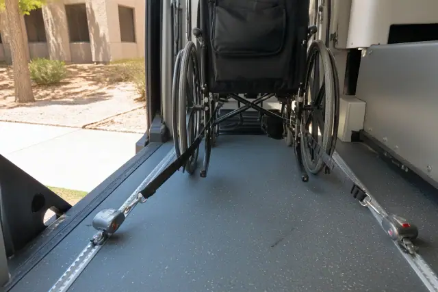 Four-point tie-down straps anchored to a wheelchair securement station floor in Phoenix, AZ.