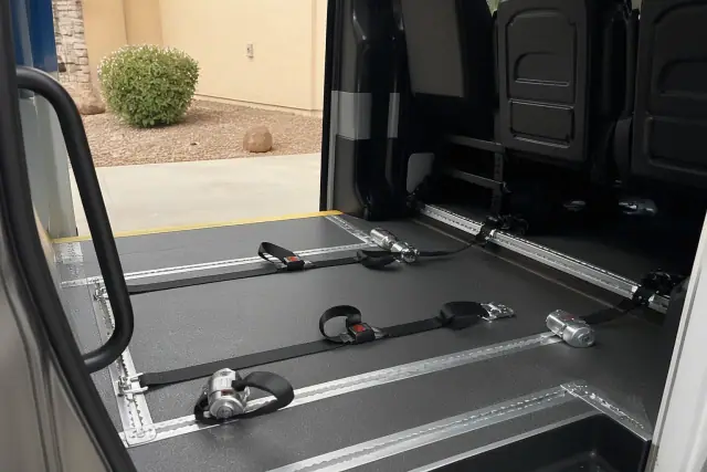 Wheelchair securement station with tie-down straps inside a medical transport van in Peoria, AZ.