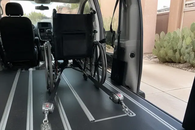 Wheelchair securement station with four-point tie-down straps inside a medical transport van in Chandler, AZ.