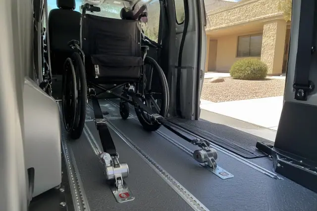 Empty wheelchair secured with tie-down straps inside an accessible transport van in Phoenix, AZ.