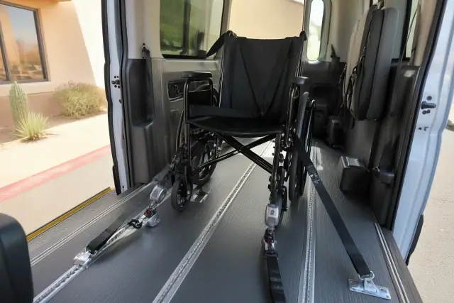 Empty wheelchair secured with four-point tie-down straps in a medical transport van in Scottsdale, AZ.