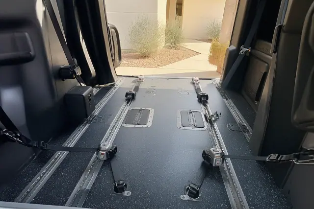 Interior of a wheelchair accessible van with tie-down straps and desert scenery visible in Phoenix, AZ.