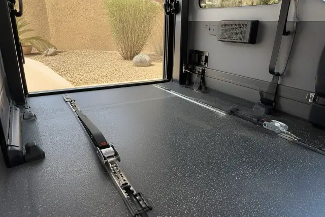 Wheelchair securement station with four-point tie-down straps in a medical transport vehicle in Phoenix, AZ.