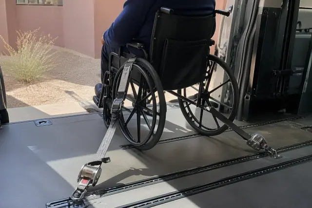 Wheelchair secured with four-point tie-down straps inside a medical transport van in Mesa, AZ.