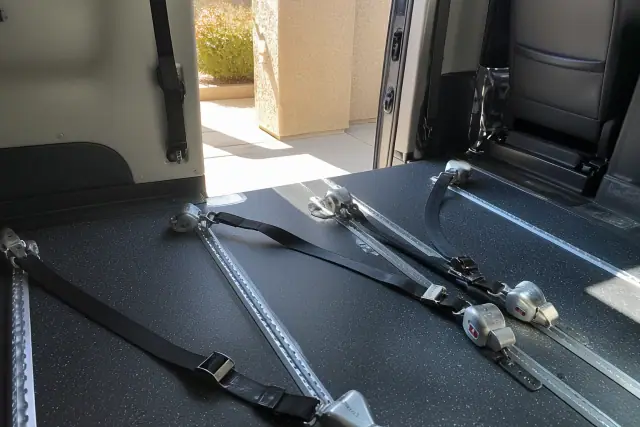 Wheelchair securement station with tie-down straps inside a transport vehicle in Gilbert, AZ.