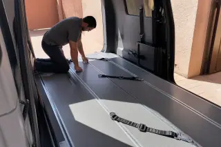 Technician inspecting floor tracks and tie-down straps in a wheelchair van in Phoenix, AZ.