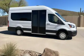 A clean wheelchair transport van parked on a driveway in Phoenix, AZ with its side entry ramp resting on the ground.