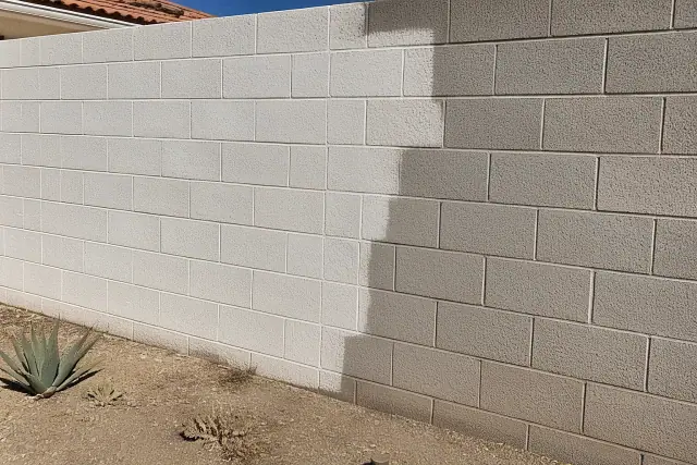 Half-finished acrylic masonry paint application on a concrete block wall at a residential jobsite in Phoenix, AZ.