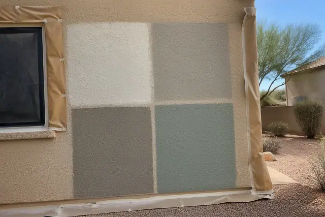 Large square paint swatches tested on a textured stucco wall at a residential jobsite in Phoenix, AZ.