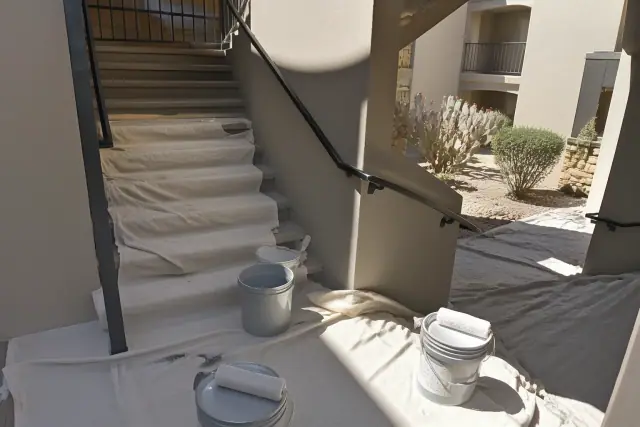 Painter's equipment on drop cloths in a residential stairwell with a view of desert landscaping in Paradise Valley, AZ.