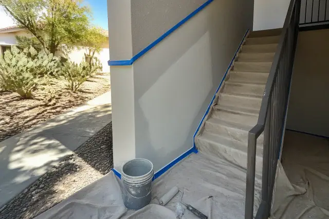 Interior stairwell painting project with drop cloths and wet paint rollers at an apartment building in Chandler, AZ.