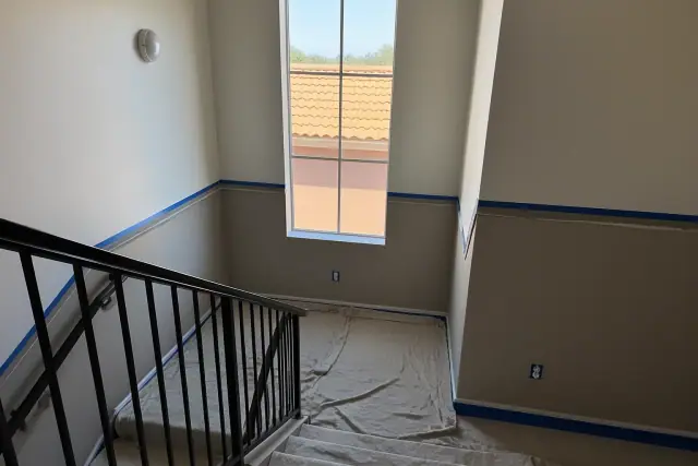 Interior stairwell of an apartment building in Phoenix, AZ, under renovation with drop cloths and painter's tape.