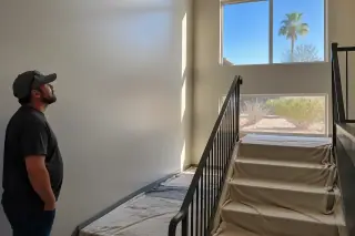 Project manager inspecting a freshly painted stairwell with drop cloths and desert views in Phoenix, AZ.