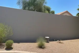 Uniformly painted masonry block wall with cleanup brushes near the base in a Phoenix, AZ home.
