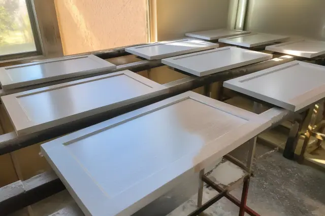 Dismantled cabinet doors on drying racks during a painting project in a Phoenix, AZ workshop.