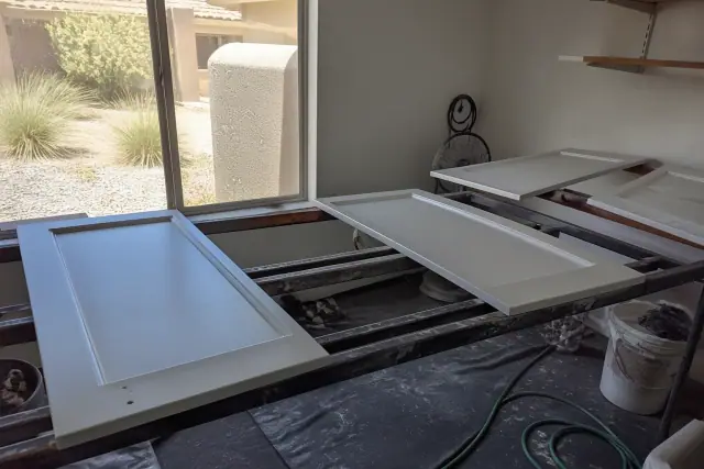 Cabinet doors with a smooth satin finish drying on racks in a workshop in Glendale, AZ.