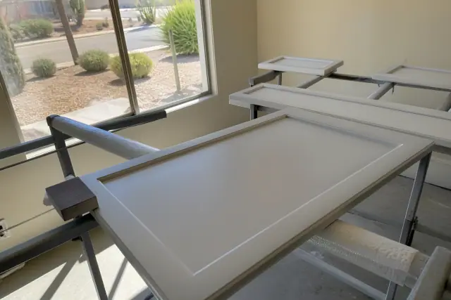 Cabinet doors on drying racks with a sanding block in a workshop in Chandler, AZ.