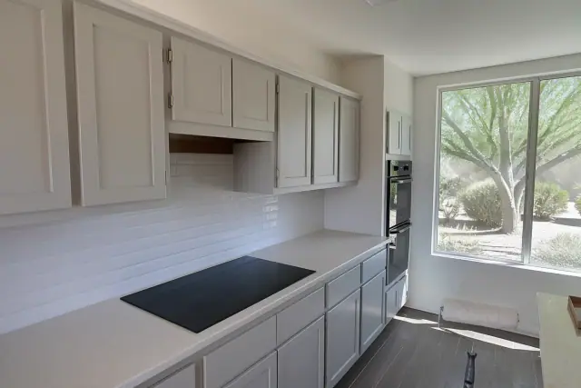 Freshly painted shaker cabinets in a residential kitchen in Surprise, AZ, viewed from a gravel yard.